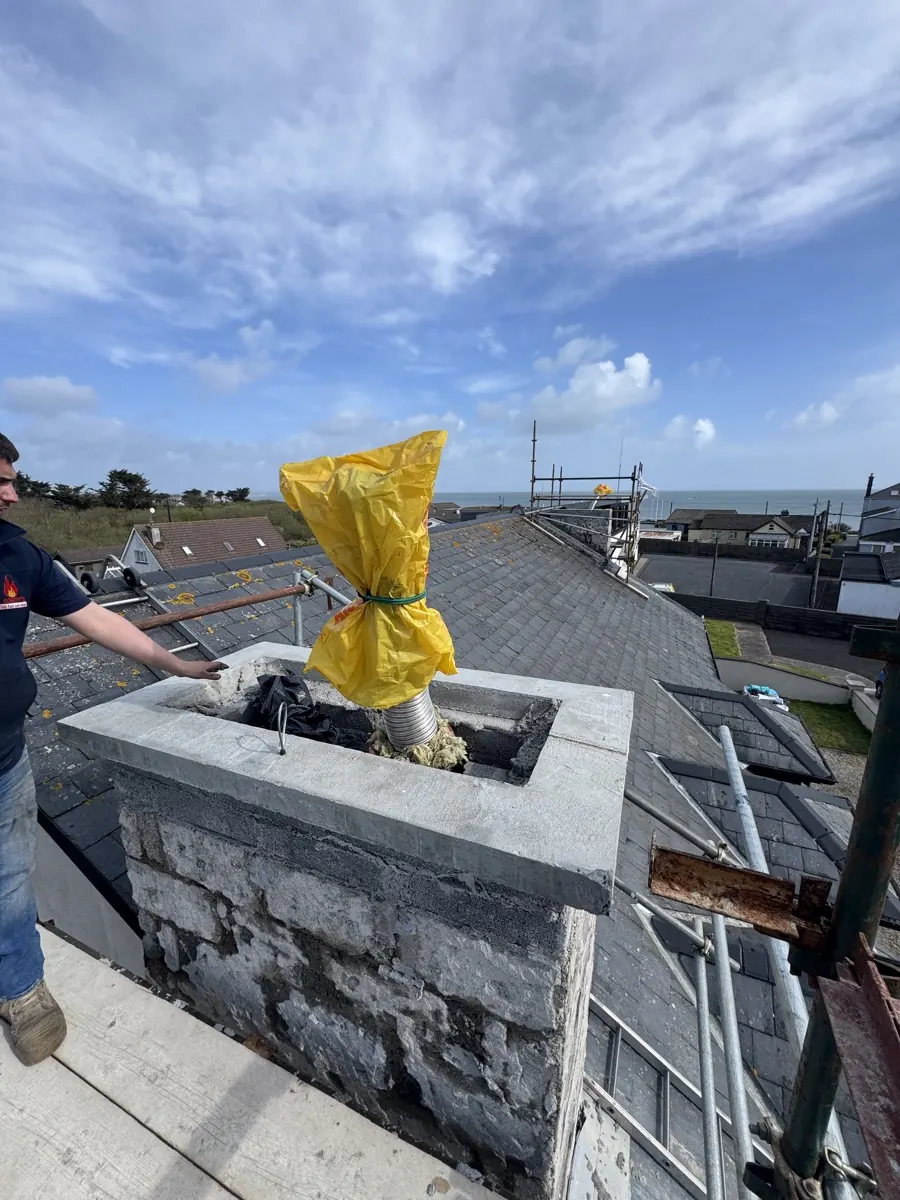 Johnny Roberts at the top of a rebuilt chimney stack with a new flue liner being fitted