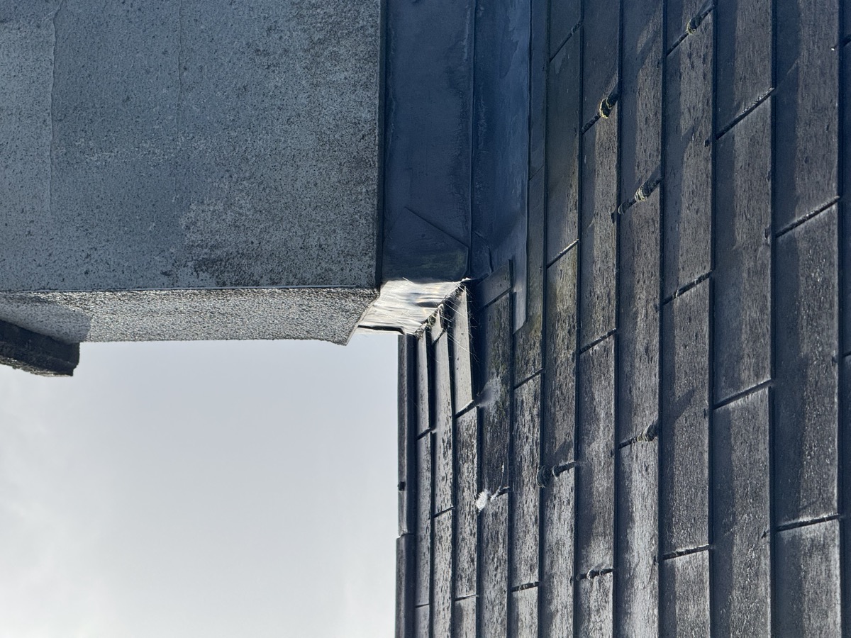 Storm damage — lifted slates at chimney base
